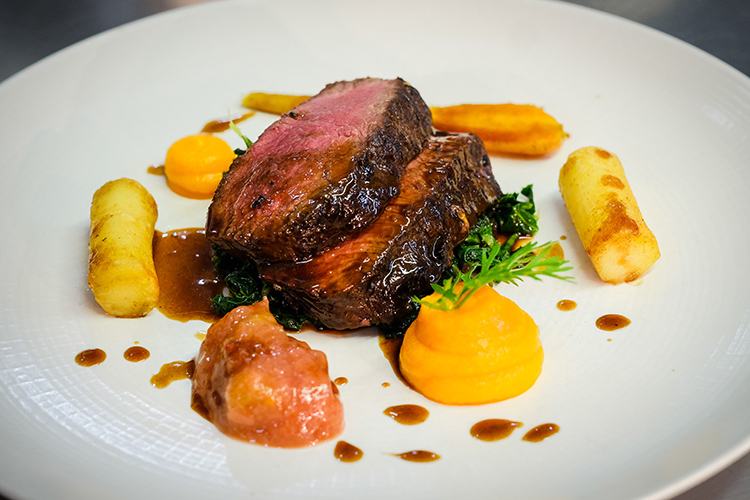 Juniper rolled venison loin served on a bed of kale with fondant potatoes, carrot puree, jus and a rhubarb and ginger chutney